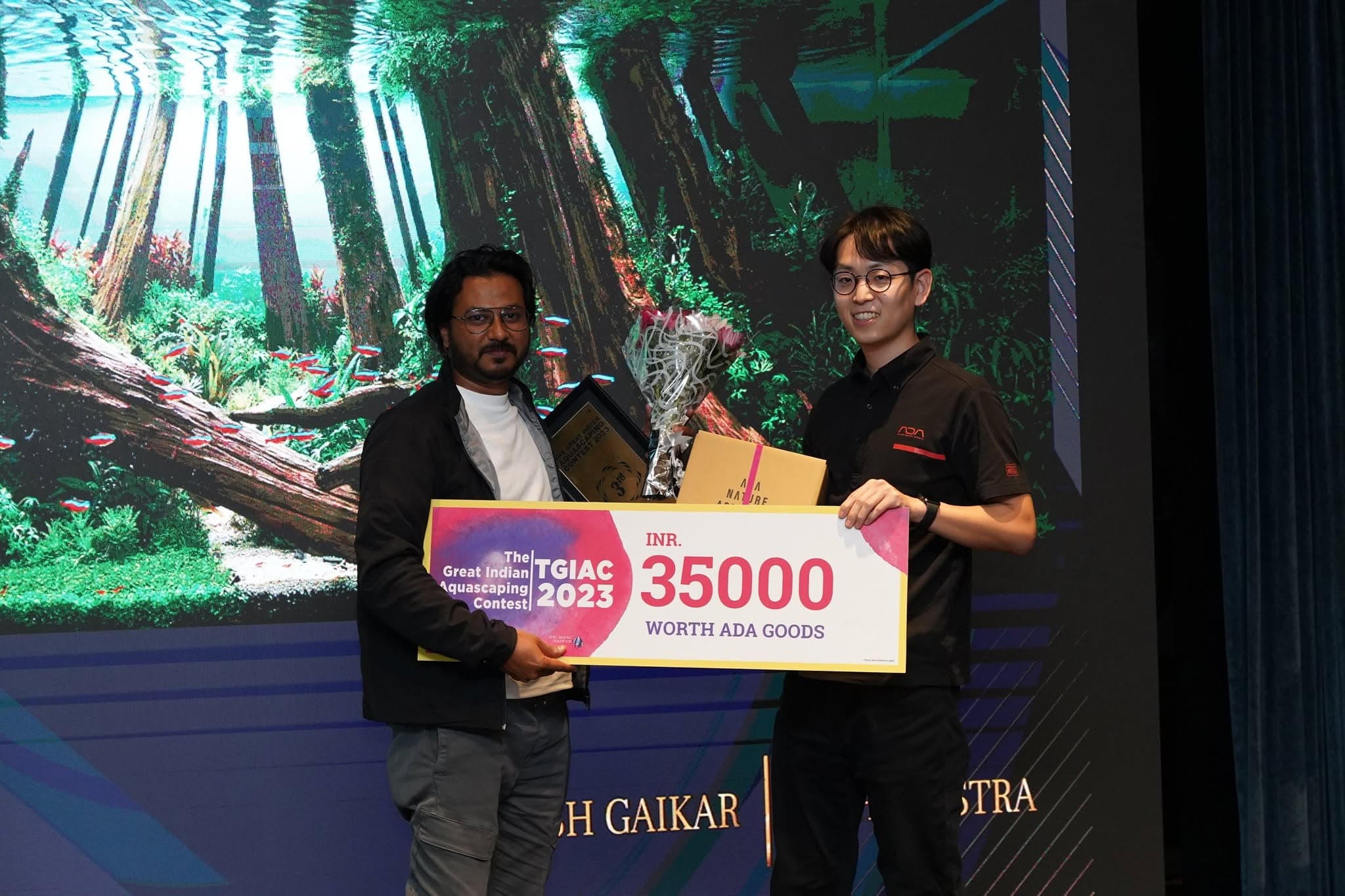 Prize handover on stage with a forest-scape backdrop